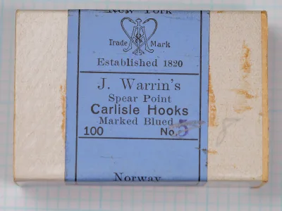 Cardboard box lid with a blue label band printed J. Warrin's Spear Point Carlisle Hooks Marked Blued, 100, with a purple 5 after No. and staining beside the label.